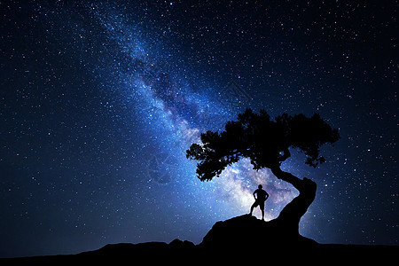 银河个男人的轮廓银河系夜空中星星,老树个独自站山上背包的人的轮廓蓝色银河旅行者旅行背景树下个图片