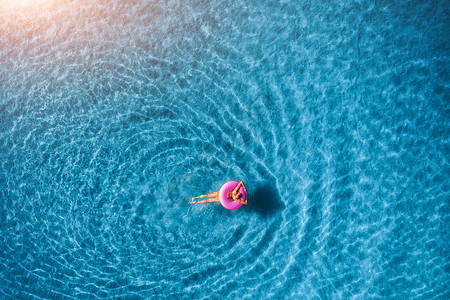 日出时,轻女子透明的蓝色海洋中的粉红色游泳圈上游泳的鸟瞰夏天空中海景与女孩,清澈的水早上的风景旅行度假图片