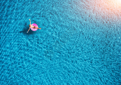 日落时,轻女子透明的蓝色海洋中游泳,粉红色的游泳圈上游泳夏季空中景观与女孩,清澈的水晚上的风景欧洲旅行图片
