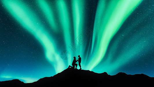 个男人山上向他的女朋友求婚的北极光剪影夜空景观,北极光,夫妇人民情人北极光旅行北极光夫妇的剪影图片