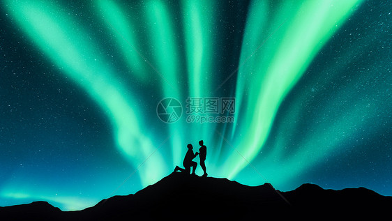 个男人山上向他的女朋友求婚的北极光剪影夜空景观,北极光,夫妇人民情人北极光旅行北极光夫妇的剪影图片