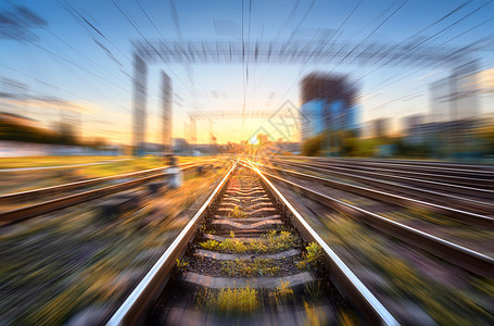 铁路与运动模糊效果日落工业景观与模糊的火车站,建筑物,绿草,蓝天橙色的阳光晚上铁路轨道背景铁路与运动模图片