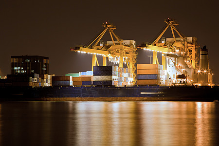 大型集装箱货运船与工作重机船厂夜间物流进口出口背景图片