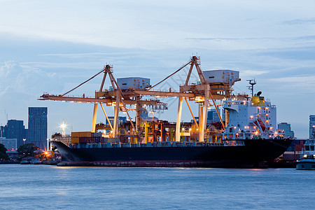 集装箱货运船与工作重机桥船厂晚上,为物流进口出口背景图片