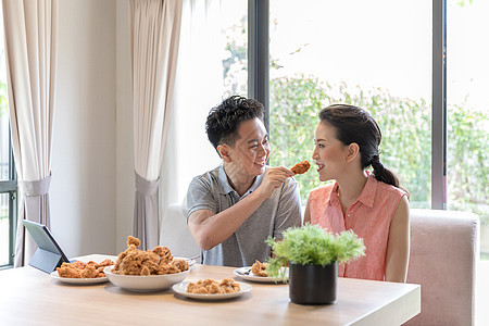 轻的亚洲夫妇吃炸鸡当代房子的客厅为现代生活方式的图片