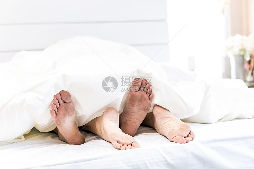 轻感的情侣躺酒店的床上,拥抱白色的床单上,闭上双腿,浪漫的心情图片