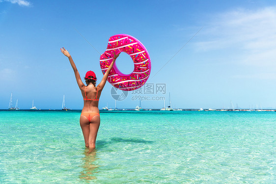 美丽的轻女子穿着橙色比基尼,粉红色甜甜圈游泳环透明的海洋阳光明媚的夏天热带景观感的苗条女孩的背部,清澈的水,蓝天图片