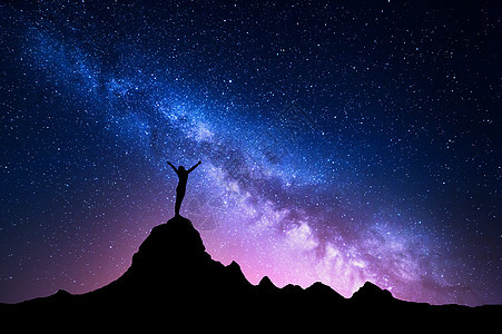 银河系的景观五颜六色的夜空,星星轮廓,个站立的快乐的女人,举的手臂,山峰上,美丽的星系的背景蓝色银河系岩石图片
