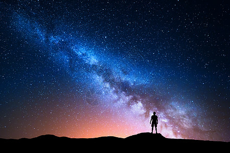 银河系美丽的夜空,星星个独自站山上的人的轮廓蓝色的银河,红光人山上背景与星系个人的轮廓宇宙图片