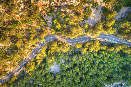 空中观看山曲线道路与汽车,绿色森林日落欧洲夏季景观与沥青道路,树木岩石上穿过公园的高速公路飞行无人机的顶部视图图片