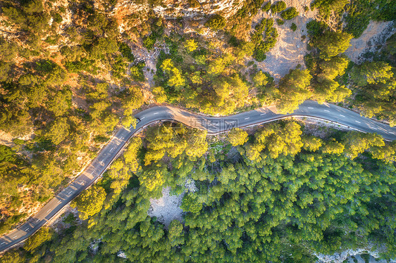 空中观看山曲线道路与汽车,绿色森林日落欧洲夏季景观与沥青道路,树木岩石上穿过公园的高速公路飞行无人机的顶部视图图片