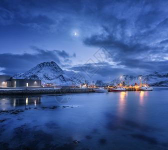 渔船靠近码头的海上雪山星空与月亮卢福滕群岛,挪威冬季景观与船舶,建筑物,照明,高岩石云图片