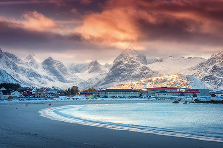 美丽的北极沙滩,冬季挪威洛福滕群岛日落时蓝色的大海风景雪山,天空橙色的云,水,村庄建筑,步行的人自然图片