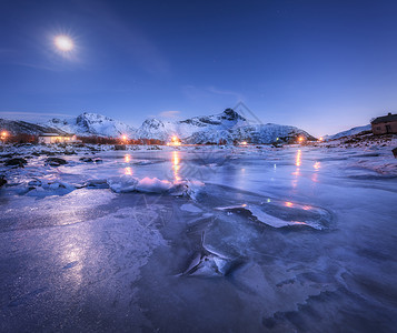 冰冻的海岸,美丽的雪覆盖着山脉星空,冬天的夜晚月亮挪威洛福滕群岛美丽的峡湾北欧景观冰,岩石,建筑,照明图片