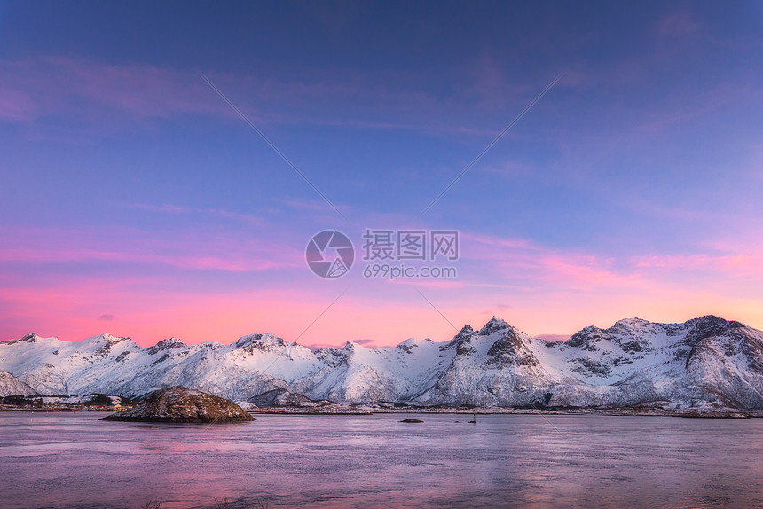 美丽的雪覆盖着群山,五彩缤纷的天空夜晚反射水中冬季景观海洋,雪岩,天空,粉红色的云,日落时的倒影黄昏时分,挪威的洛图片