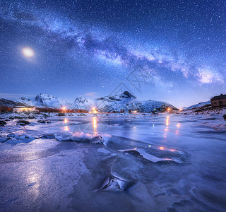 冰冻的海岸之上的银河,雪覆盖着山脉星空,挪威的夜晚,月亮冬天星系冰雪岩建筑照明银河的景观图片