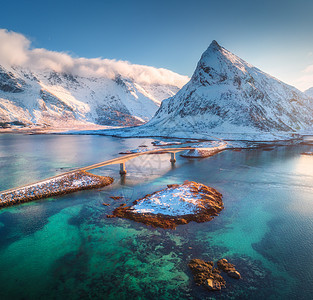 挪威洛福滕群岛海上雪山上的桥梁鸟瞰图弗雷德旺桥冬天的日落景观与碧水,岩石雪,道路天空与负荷的风景图片
