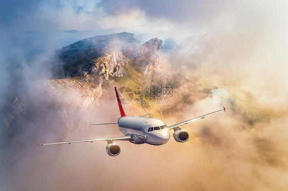 西牙日落时,飞机飞过高山低云景观与客机,多云的天空,岩石,森林阳光商业飞机上的商务旅行空中视野旅程图片