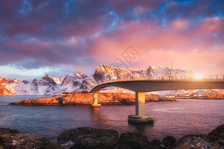 美丽的桥梁雪山冬季日出时洛福滕岛,挪威风景桥,五颜六色的天空粉红色的云,岩石雪中,石头海里太阳欧洲旅行图片