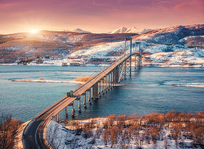 挪威洛福滕群岛日落时的神奇桥梁空中冬季景观,道路上汽车,蓝色的大海,树木,雪山,五颜六色的橙色天空,云彩阳光北欧的风图片