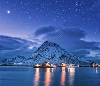 渔船靠近码头的海上雪山星空紫色的天空与月亮卢福滕群岛,挪威冬季景观与船舶,建筑物,照明,岩石云图片