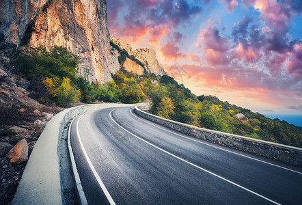 日落时的山路美丽的天空五颜六色的景观,高岩石,蜿蜒的沥青路,树木蓝天与红色橙色的云秋天旅行山中高速公路的风图片