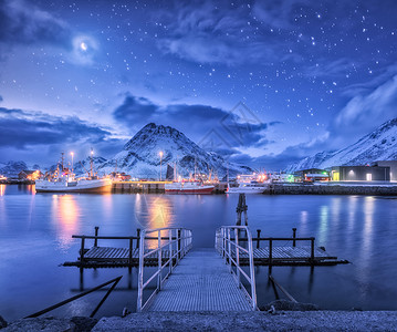渔船靠近码头的海上雪山星空与月亮卢福滕群岛,挪威冬季景观与桥梁,船舶,建筑,照明,岩石云图片