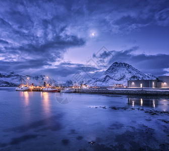 渔船靠近码头的海上雪山星空与月亮卢福滕群岛,挪威冬季景观与船舶,建筑物,照明,高岩石云图片