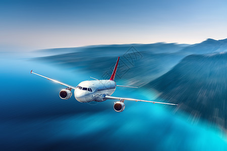 飞机日落时飞过蔚蓝的大海山脉风景与客机,岛屿黄昏运动模糊效应的客机商务旅行空中视野商业飞机图片