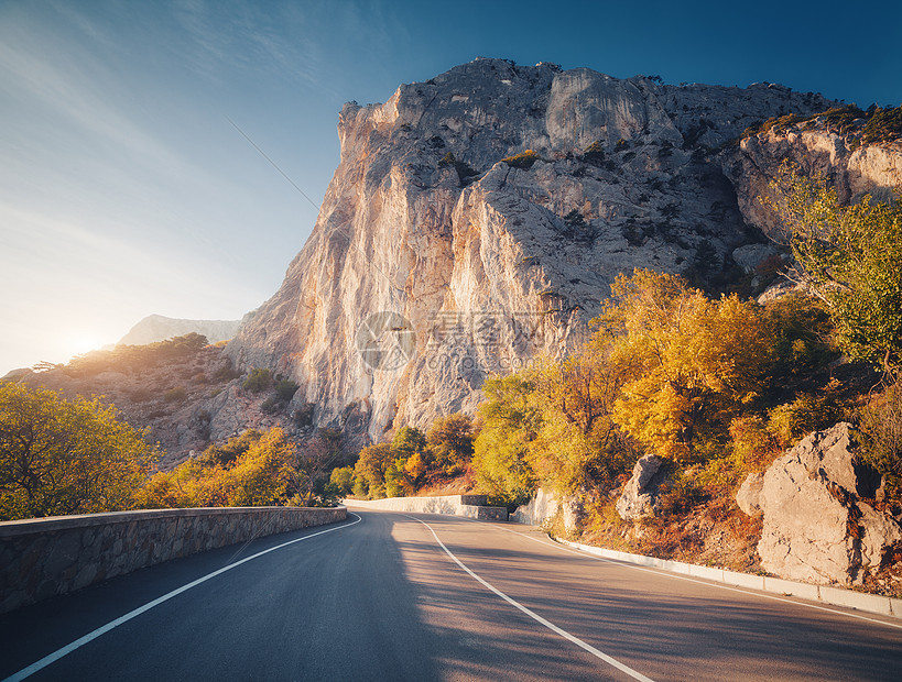 日落时的山路美丽的天空五颜六色的景观,高岩石,蜿蜒的沥青路,橙色的叶子,蓝色的天空,秋天的云旅行山中巷道的风景图片