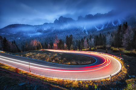 模糊的汽车前灯蜿蜒的道路上,秋天的夜晚,云层很低壮观的景观与沥青路,轻小径,雾林,岩石蓝天汽车路上行驶图片