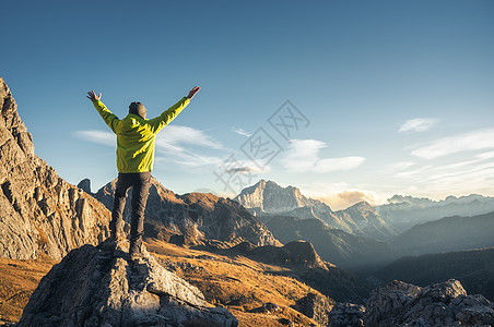 运动的人站石头上,举手臂日落时抗山谷快乐的轻人,岩石,秋天的森林蓝天白云石,意大利旅行者高山上徒步旅行图片