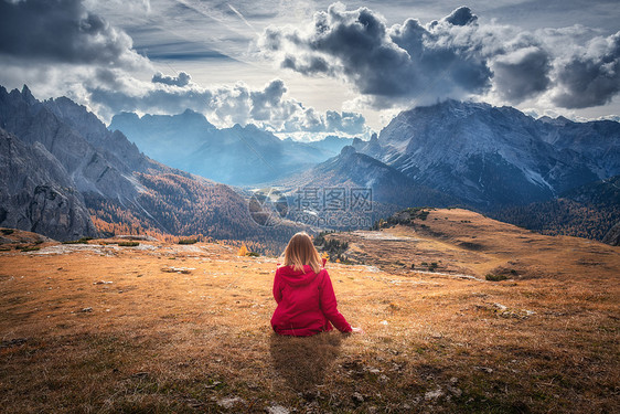 轻的女人正坐山上,秋天的白云石,意大利的壮丽的山风景与女孩,多云的天空,橙色的草,高岩石与森林秋天意大利阿尔卑斯图片