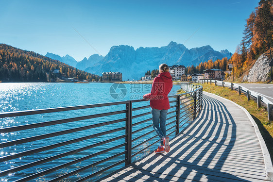 秋天日出时,站米苏丽娜湖海岸的轻女子意大利白云石风景与女孩穿着红色夹克,倒影水,建筑物,蓝天意大利阿尔卑斯山图片