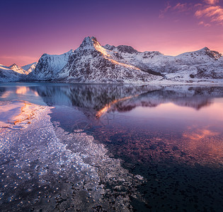 雪山的鸟瞰,蓝色的大海霜冻的海岸,挪威洛福滕岛五颜六色的日落时,水紫色的天空中反射冬天的风景雪覆盖的岩石,峡湾冰图片