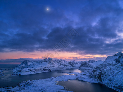 挪威洛福腾岛的雪山海洋彩色多云天空的空中景色冬季景观雪覆盖的岩石海岸日落的天空黄昏时挪威峡湾的顶部景色图片