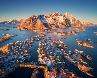 挪威洛福滕岛日落时亨宁斯娃的鸟瞰图冬季景观建筑雪山蓝海房屋的顶部景观,港口的船只,岩石天空著名的渔村图片
