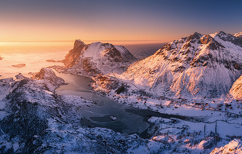 挪威洛福滕群岛日落时美丽峡湾的鸟瞰图冬天的风景雪山,蓝色的大海橙色的天空太阳雪路村庄中岩石的顶部景观北部海图片