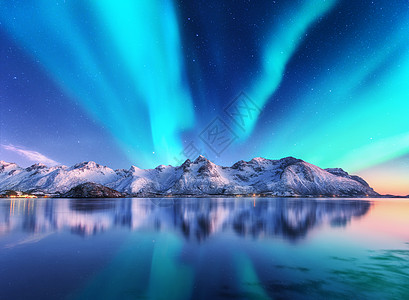 北极光雪覆盖了挪威洛芬岛的山脉北极光星空,极地的灯光雪石反射水中夜间冬季景观与极光,海洋旅行北极光雪背景图片