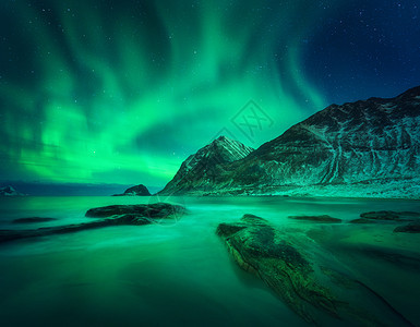 雪山沙滩上的北极光,石头挪威洛福滕岛的北极光极地灯光的星空夜间冬季景观与极光,海洋与模糊的水北极光,雪山图片