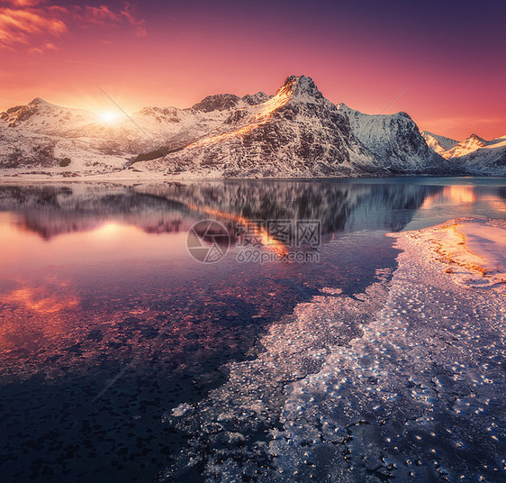 雪山的鸟瞰,蓝色的大海霜冻的海岸,挪威洛福滕岛五颜六色的日落时,水紫色的天空中反射冬天的风景雪覆盖的岩石,峡湾冰图片