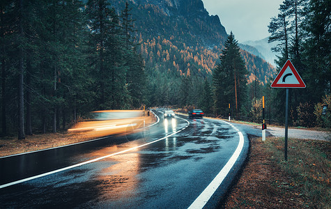 秋天的森林里,道路上模糊的汽车雨中运动阴雨天完美的沥青山路巷道,意大利阿尔卑斯山的松树运输雾林中的公路旅图片