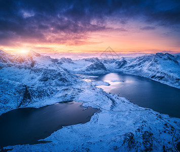 挪威洛福滕群岛日落时,空中俯瞰雪山海洋彩色多云天空冬天的景观雪覆盖的岩石海岸蓝天黄昏时挪威峡湾的顶部景色图片