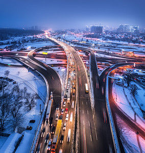 雾中夜间俯瞰现代城市的道路公路交通的顶部视图冬季城市景观与高架道路,汽车,建筑,照明欧洲的立交桥高速公路图片