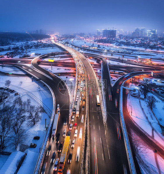 雾中夜间俯瞰现代城市的道路公路交通的顶部视图冬季城市景观与高架道路,汽车,建筑,照明欧洲的立交桥高速公路图片