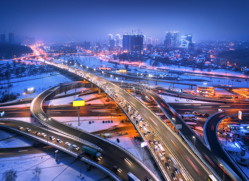 雾中夜间俯瞰现代城市的道路公路交通的顶部视图冬季城市景观与高架道路,汽车,建筑,照明欧洲的立交桥高速公路图片