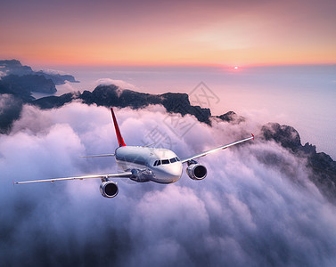 客机日落时飞过云层风景与白色飞机,低云,海岸,紫色的天空黄昏飞机正降落出差商业飞机旅行空中视野图片