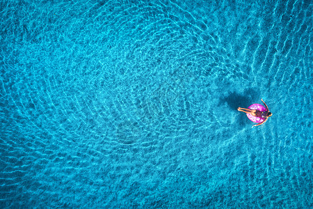 日出时,轻女子透明的蓝色海洋中的粉红色游泳圈上游泳的鸟瞰夏天空中海景与女孩,清澈的水早上的风景旅行度假图片