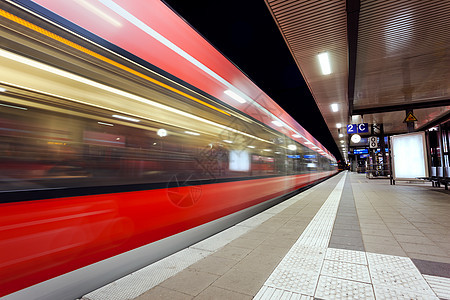 现代火车站与高速客运列车铁路轨道夜间运动纽伦堡,德国快速模糊的红色通勤列车五颜六色的工业景观图片