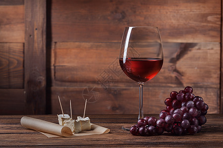 红酒璃与葡萄奶酪木制背景图片